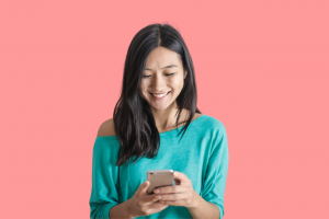 Asian girl in green shirt looking down at her mobile phone
